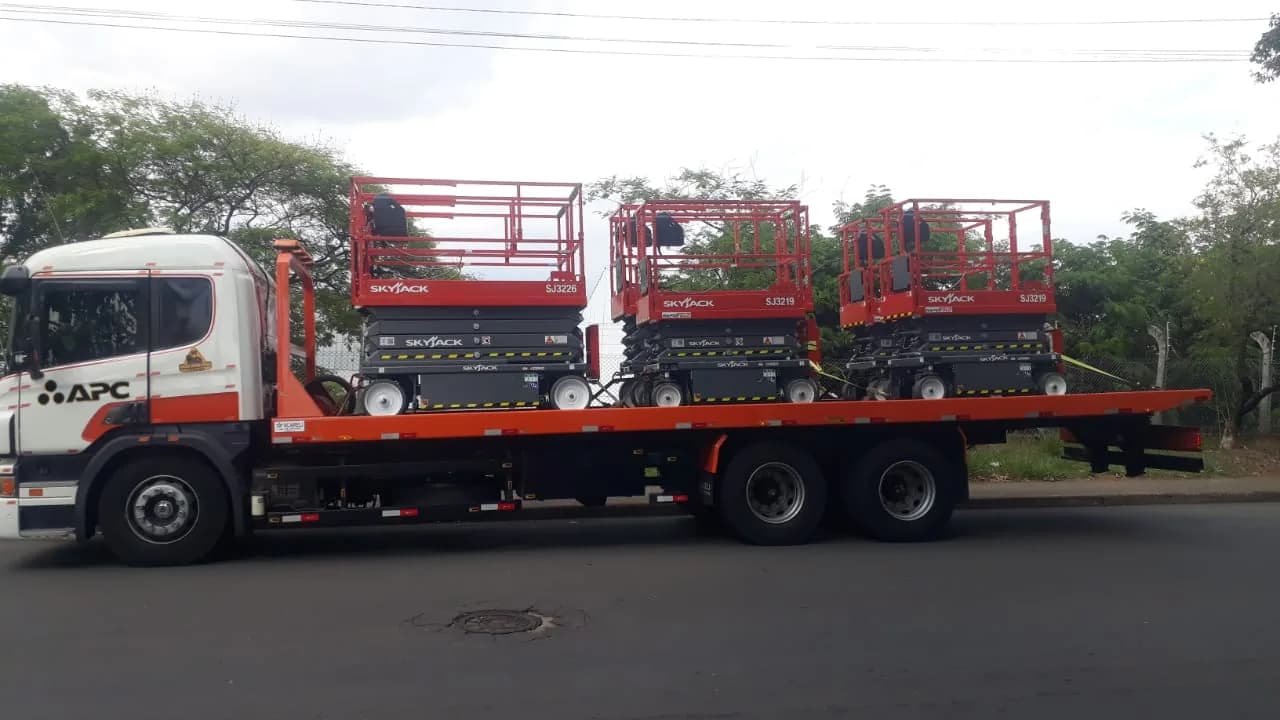Caminhão do Grupo APC carregado com três plataformas tesoura Skyjack SJ3226 e SJ3219 a caminho da entrega
