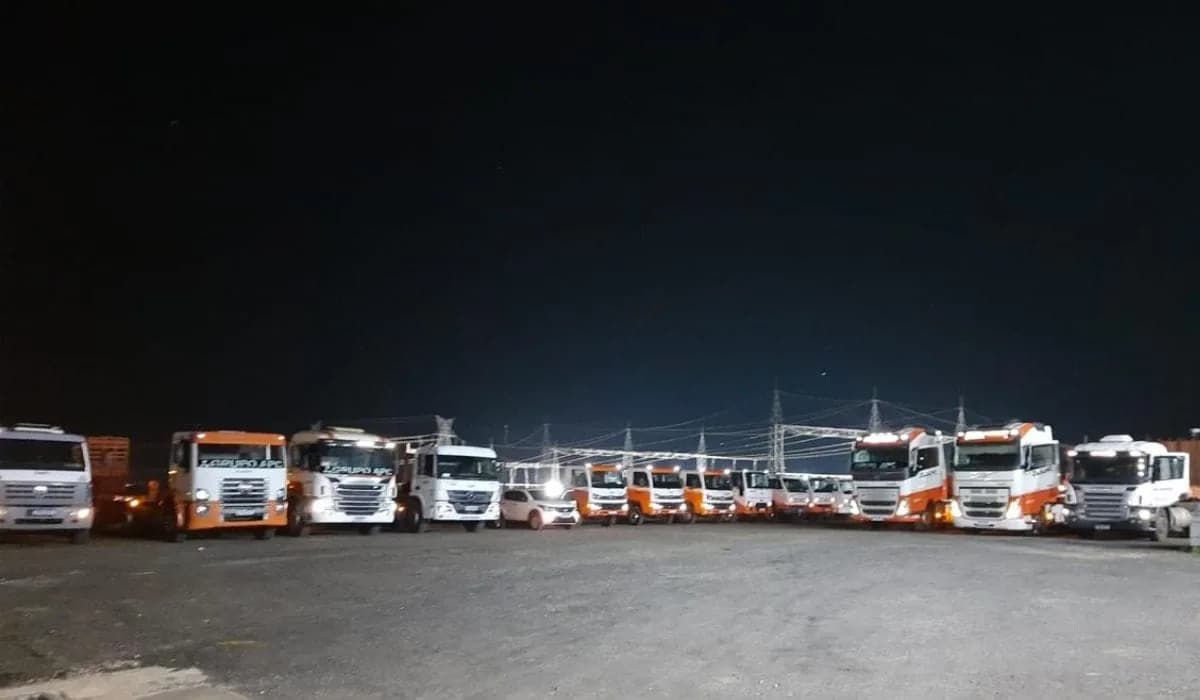Caminhões do Grupo APC estacionados lado a lado na garagem da empresa, à noite