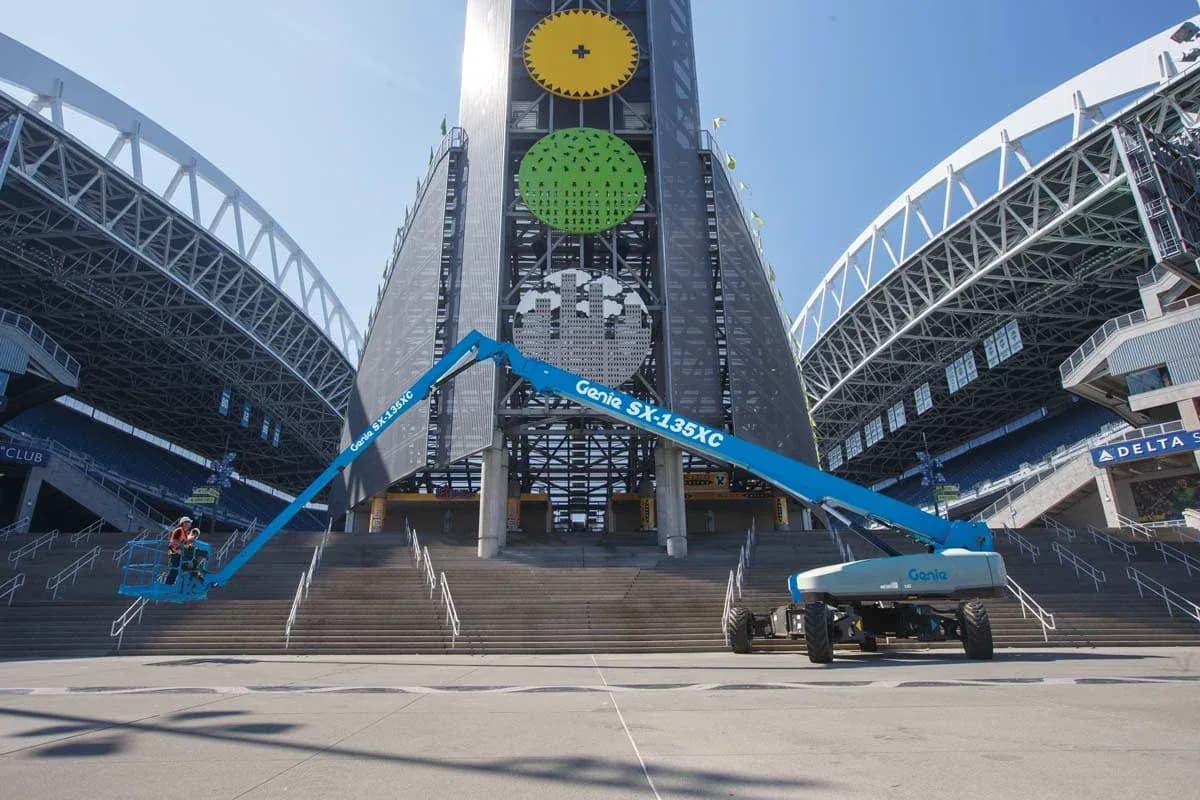 Genie SX-135 XC com a lança passando por cima de uma escadaria e a plataforma posicionada do outro lado